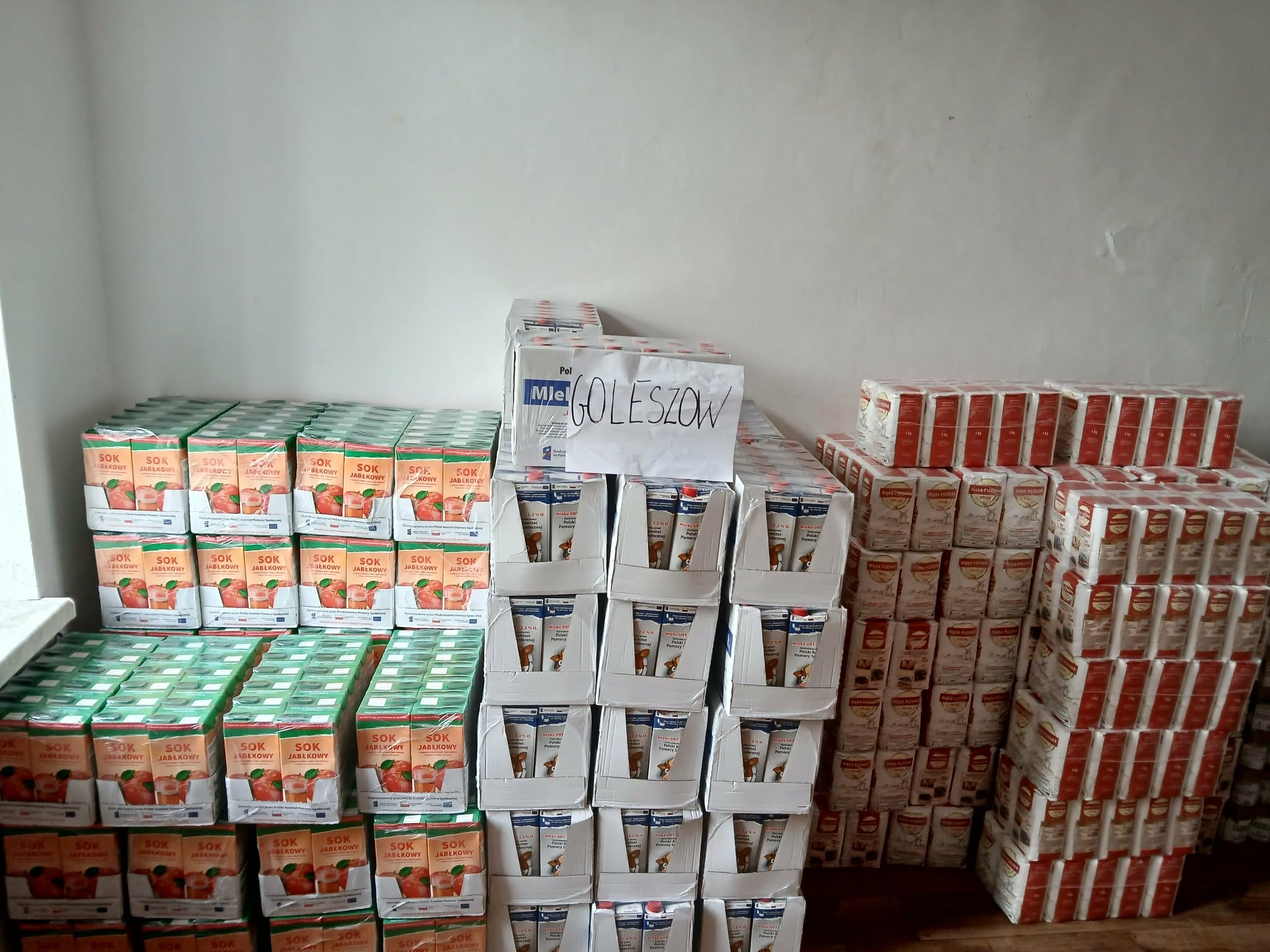 kilka rzędów katonów z żywnością na przykład mleko i sok pomarańczowy