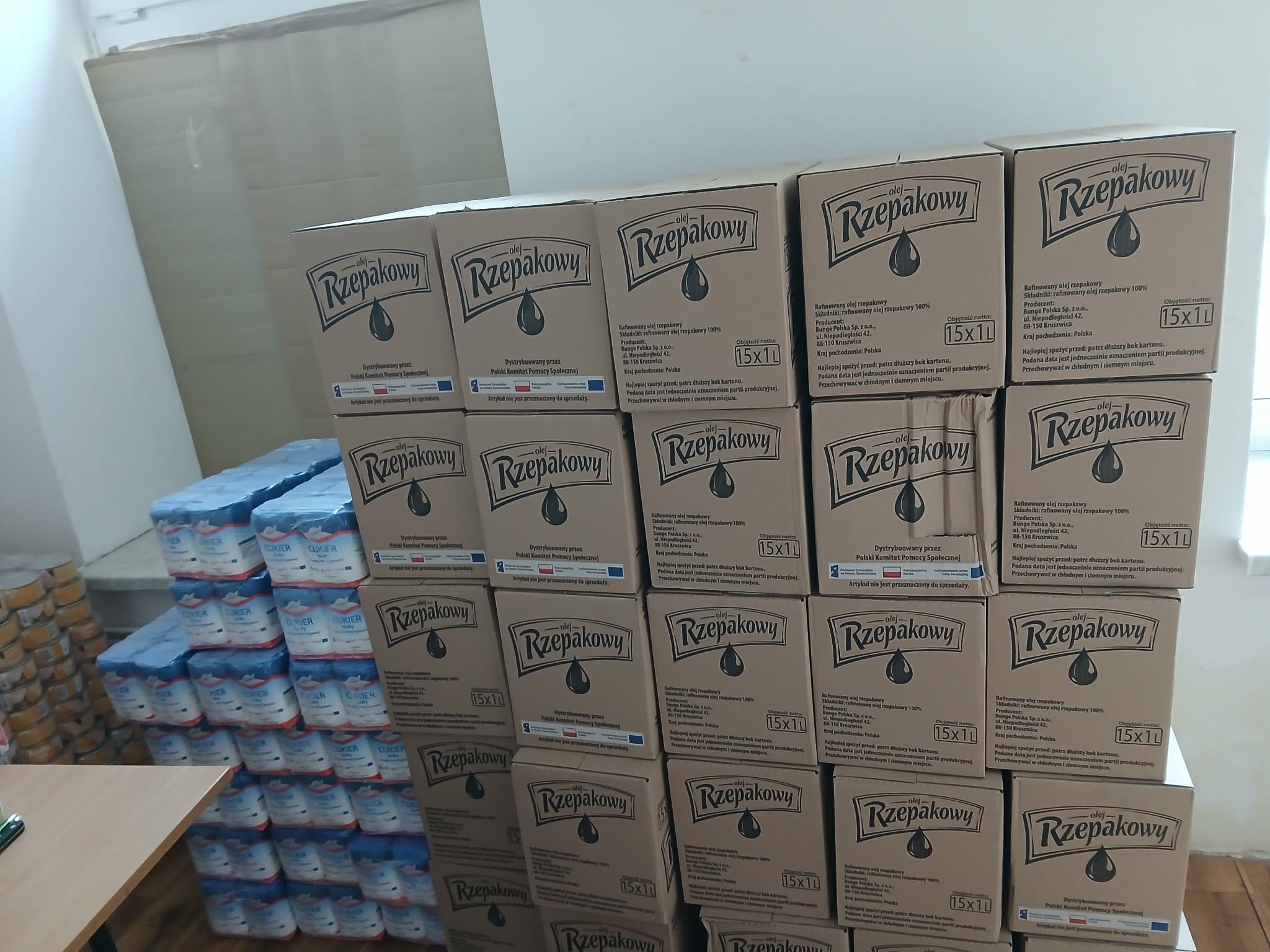 kartony ułożone w czterech rzędach z żywnością dla najuboższych mieszkańców gminy goleszów